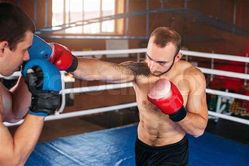 Boxer sents his opponent to the knockout. Fighting ring on the background. Box sport, stock photo