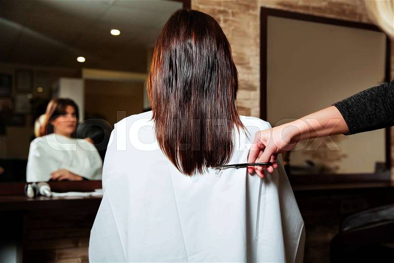 Hairdresser cut long ends to yuong woman. Hairdressing salon, stock photo