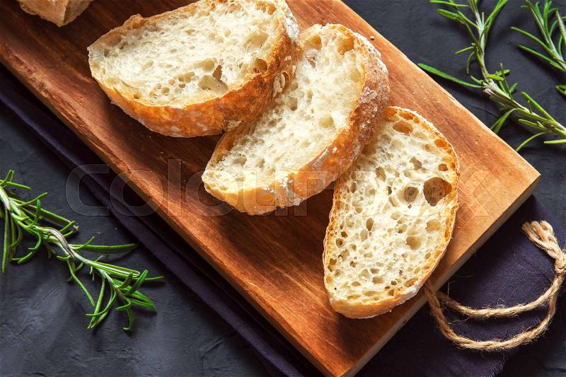 Italian bread Ciabatta and rosemary on black background - fresh homemade bread bakery, stock photo