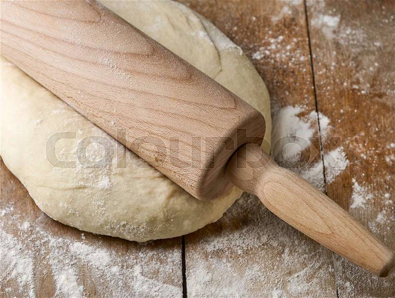 Fresh raw dough and rolling pin on rustic wooden table, stock photo