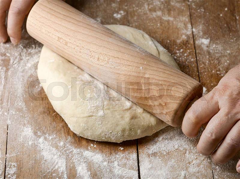 Fresh raw dough and rolling pin on rustic wooden table, stock photo