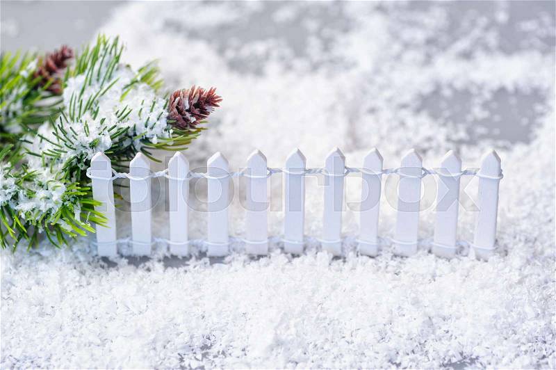 Snow-covered spruce twigs and toy white fence. Christmas installation, stock photo