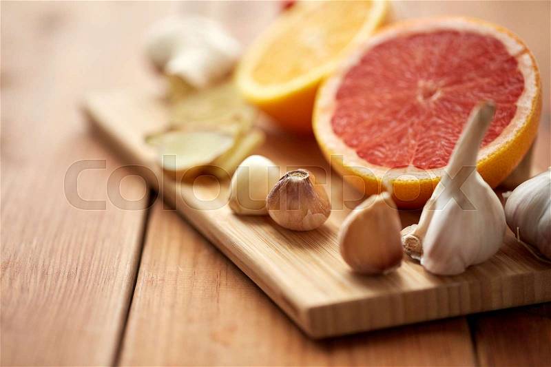 Traditional medicine, cooking and ethnoscience concept - garlic, ginger, orange and grapefruit on wooden board, stock photo