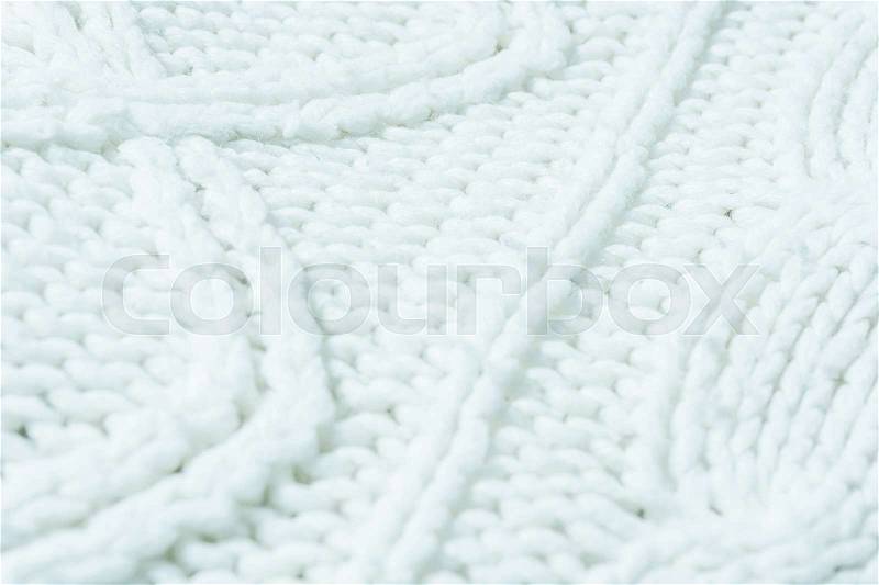 Knitted fabric texture. Knitted jersey background with a relief pattern. Braids in knitting, stock photo