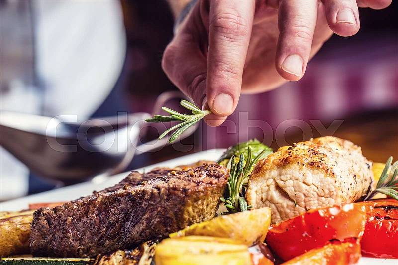 Chef in hotel or restaurant kitchen cooking only hands. Prepared beef steak with vegetable decoration, stock photo