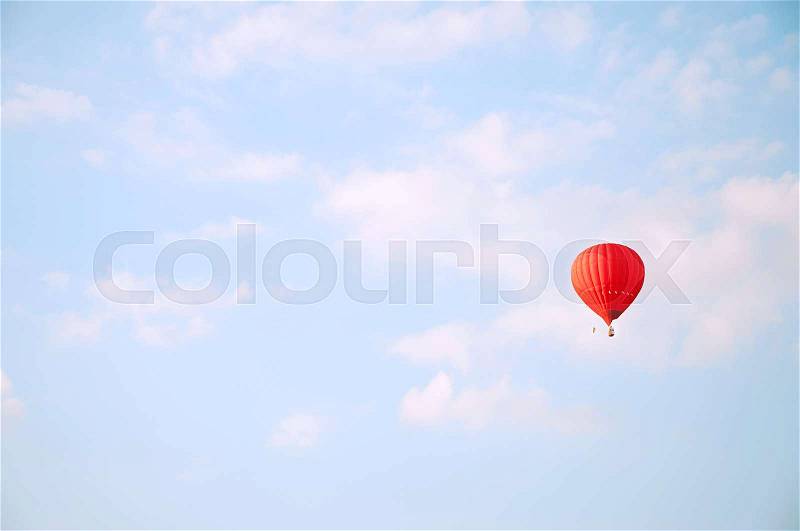 Red hot air baloon flying in blue sky with white clouds , stock photo