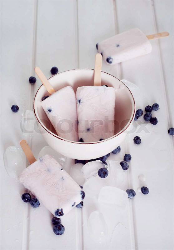 Ice popsicles with yogurt and blueberries in ice lolly mold with wooden sticks, stock photo