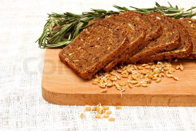 Bread, rosemary and wheat germ on a wooden board on the white linen tablecloths, stock photo