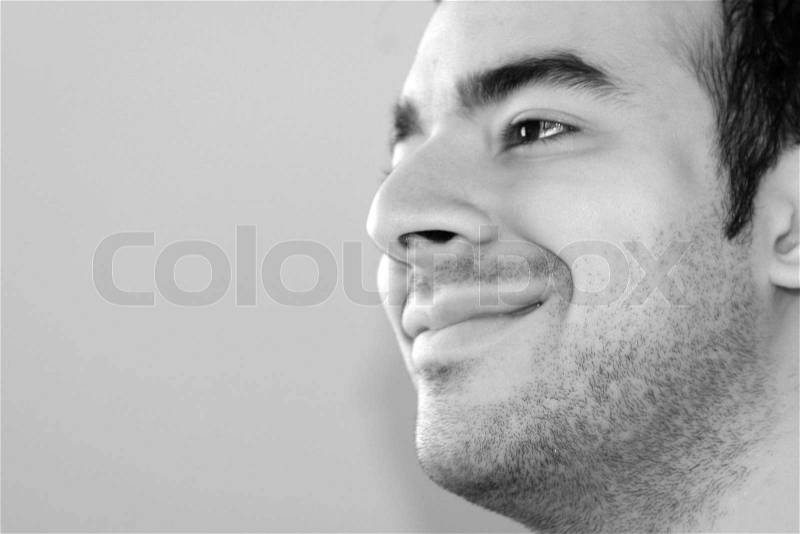 Black and white portrait of a young man smiling - plenty of copy space to the left, stock photo