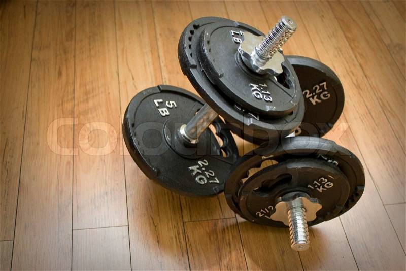 Free weights sitting on a wood floor - the perfect accessory to any home gym, stock photo
