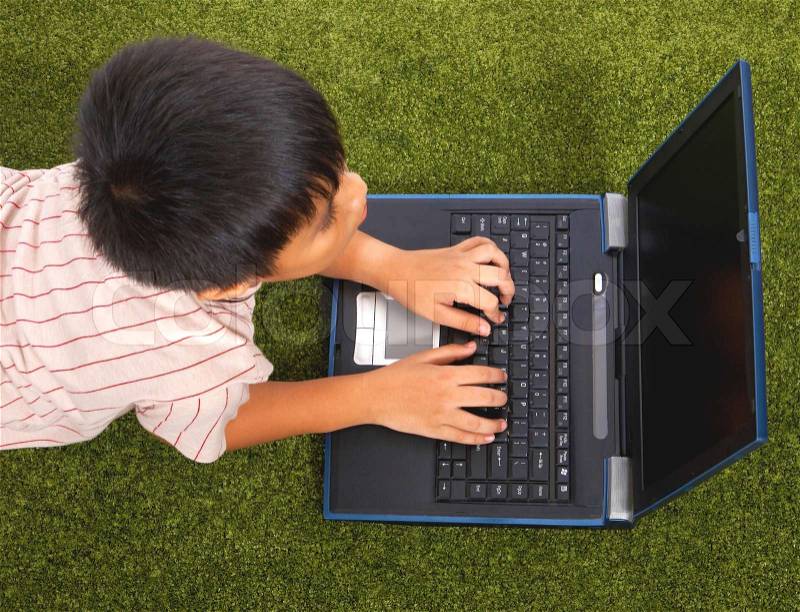 Young Kid Using His Notebook Computer For Study And Fun, stock photo