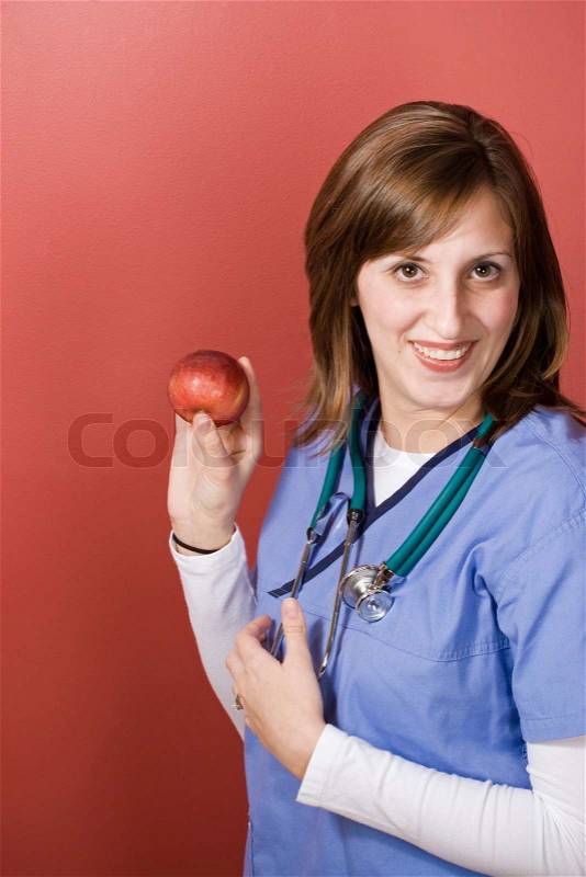 A young nurse is holding up an appleAn apple a day keeps the doctor away, stock photo