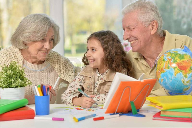 Portrait of happy Grandparents with granddaughter drawing together, stock photo