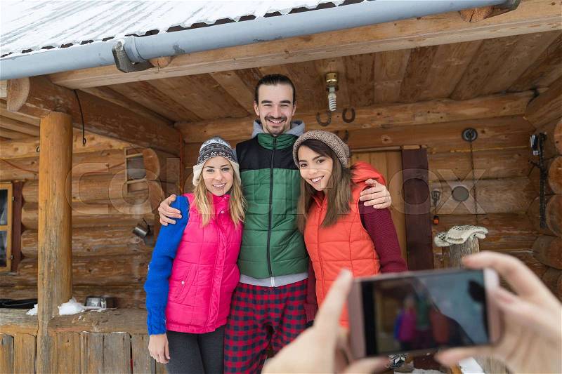 People Taking Photo On Smart Phone Group Wooden Country Mountain House Winter Snow Resort Friends On Vacation, stock photo