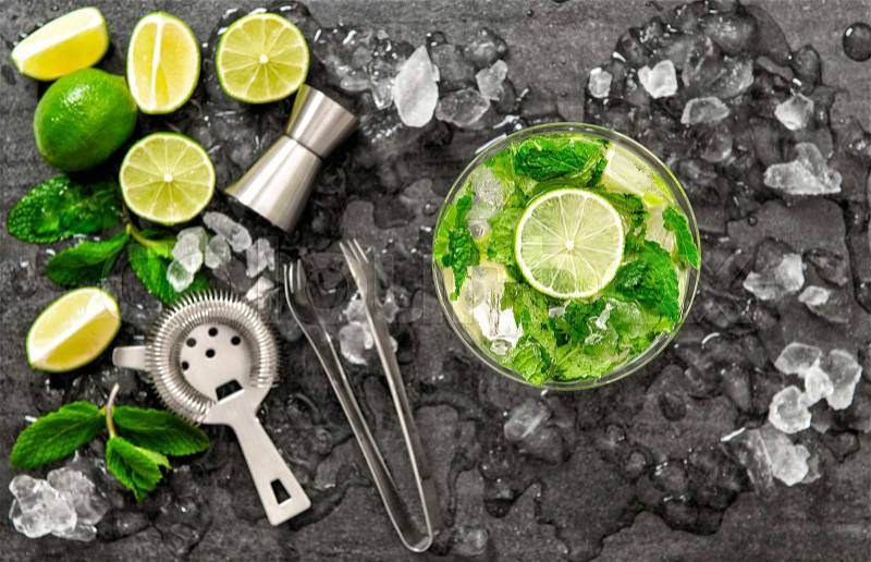 Cocktail juice with lime, mint and ice. Bar drink accessories on black table background. Alcoholic and nonalcoholic cold drinks. Selective focus, stock photo