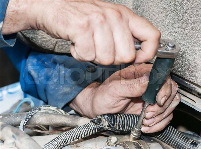 Repair of the engine. A hand with the tool. Automobile service, stock photo