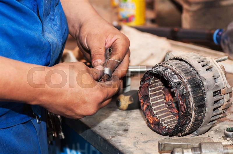 Repair of the electric generator. Hands of mechanic restores a generator, stock photo