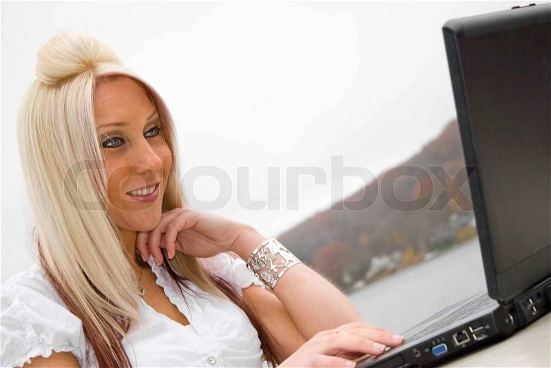 A beautiful young blonde woman in a mobile business setting with her laptop, stock photo