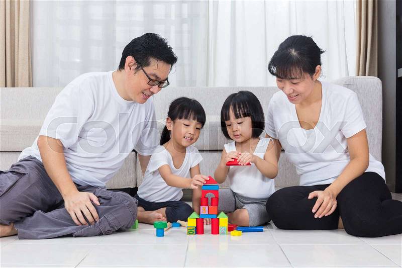 Asian Chinese parents and daughters playing blocks on the floor in the living room at home, stock photo