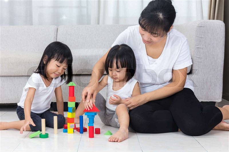 Asian Chinese mother and daughter playing blocks on the floor in the living room at home, stock photo