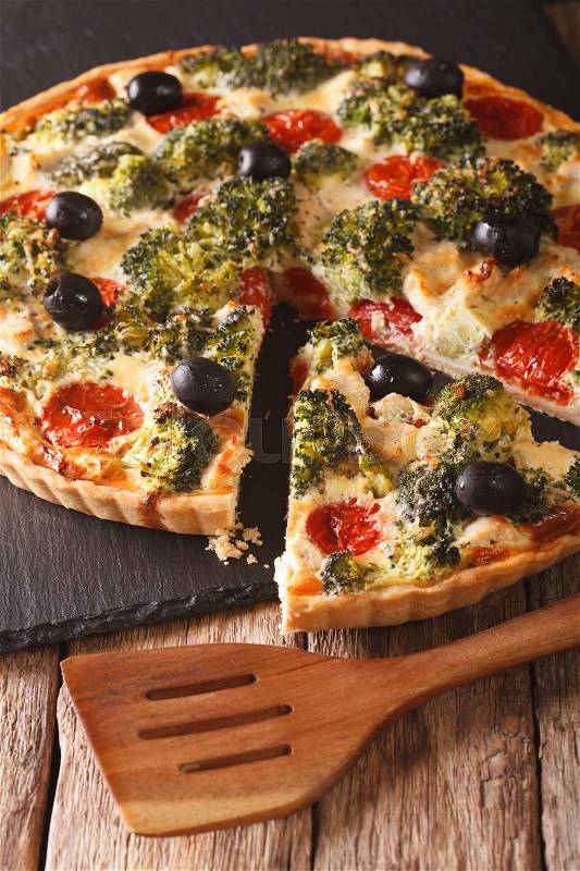 Savory food: sliced tart with chicken, broccoli, tomatoes and olives close-up on the table. vertical\, stock photo