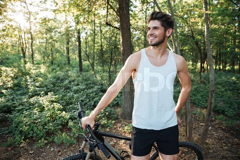 Happy cyclist in forest looking away, stock photo