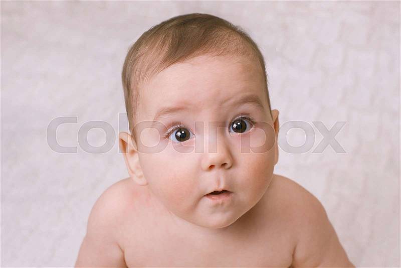 Wide eyed curious little baby staring up to the side of the camera with a mesmerised look , close up high angle, stock photo