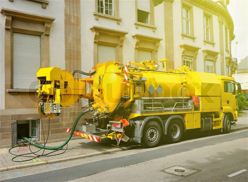 Working Sewage - sewerage - truck on city street in working process to clean up sewerage overflows, cleaning pipelines and potential pollution issues from an modern building. This type of truck is used for residential septic systems or commercial sewage s