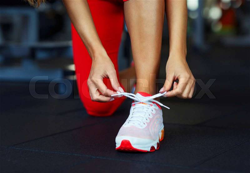 Running shoes - woman tying shoe laces. Closeup of fitness woman getting ready for engage in the gym, stock photo