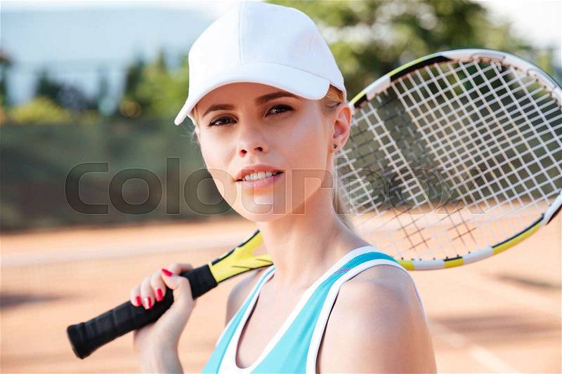 Close up tennis woman. stands sideways on court with racket. looking at camera, stock photo