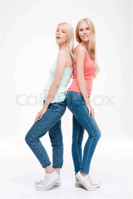 Photo of ladies dressed in t-shirts and jeans posing. Isolated over white background. Looking at the camera, stock photo