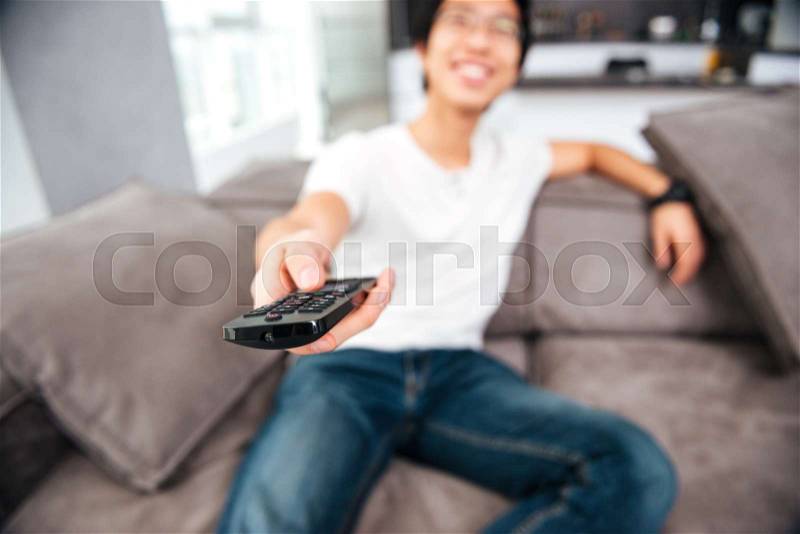 Asian man watching tv on sofa. front view, stock photo