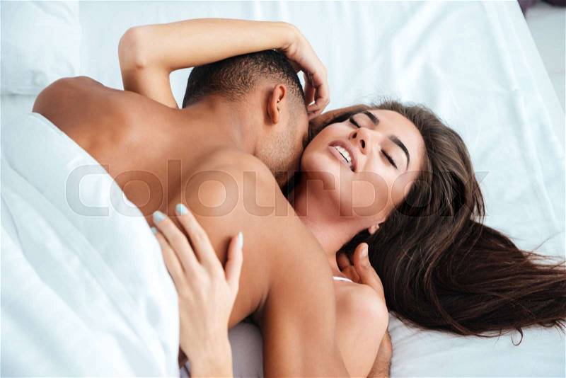 Gentle young couple lying and making love in bed at home, stock photo