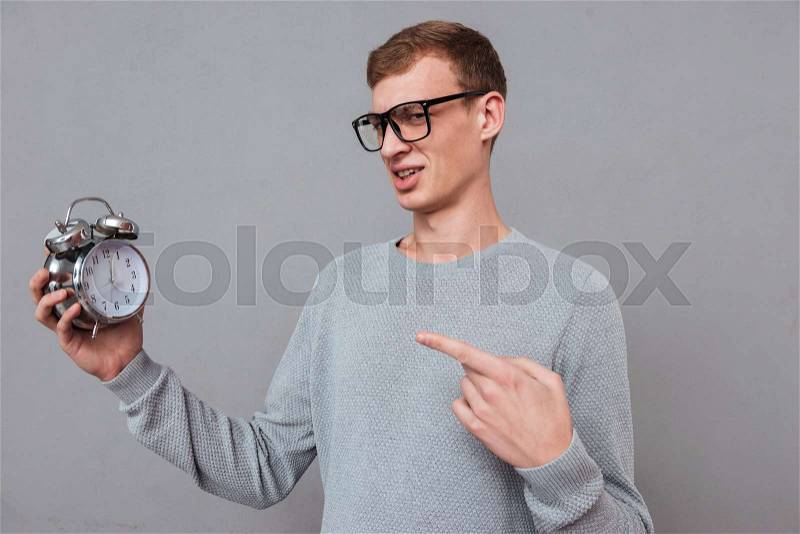 Man in glasses with clock. showing at clock. isolated gray background, stock photo