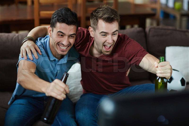 Excited fans with beer expressing satisfaction with goal of their favorite football team, stock photo