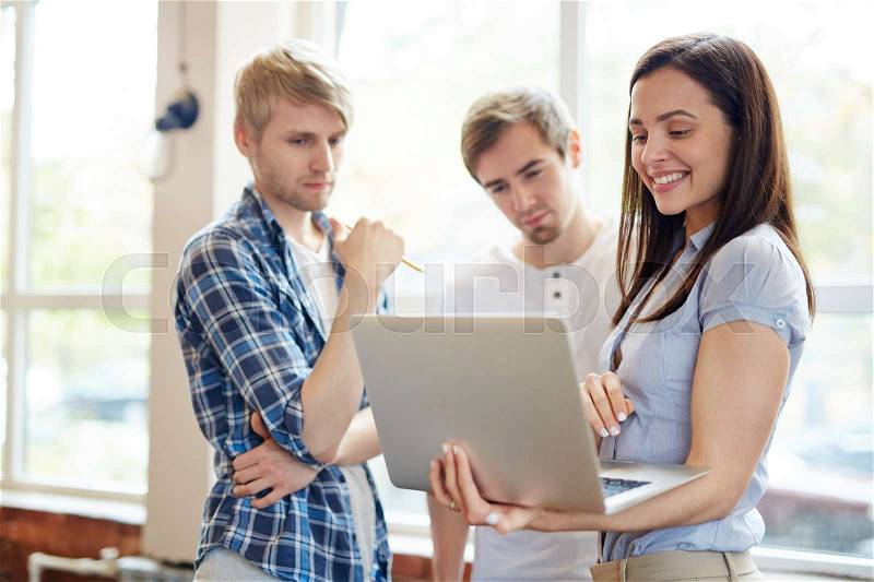 Young businesswoman with laptop and her colleagues watching online conference, stock photo