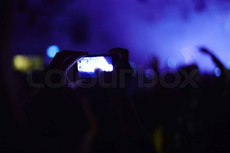 One of fans recording video of concert, stock photo