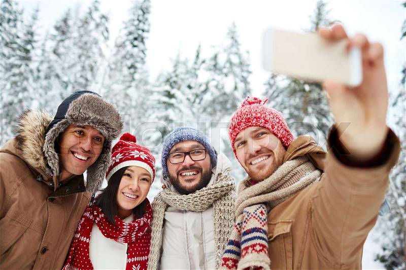 Friends with toothy smiles making winter selfie, stock photo