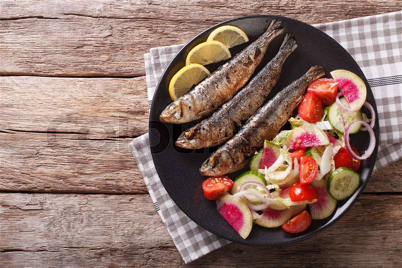 Mediterranean cuisine: grilled sardines with fresh vegetable salad close-up on a plate. horizontal view from above , stock photo