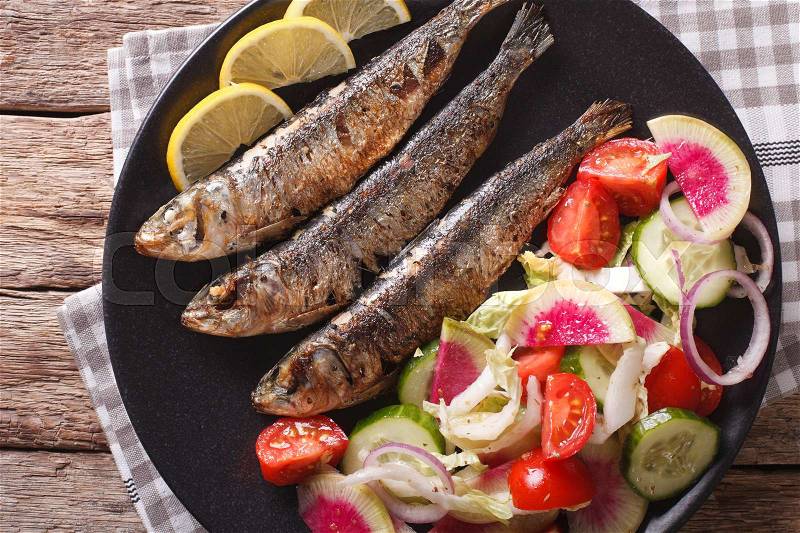 Mediterranean food: grilled sardines with fresh vegetable salad close-up on a plate. Horizontal view from above , stock photo