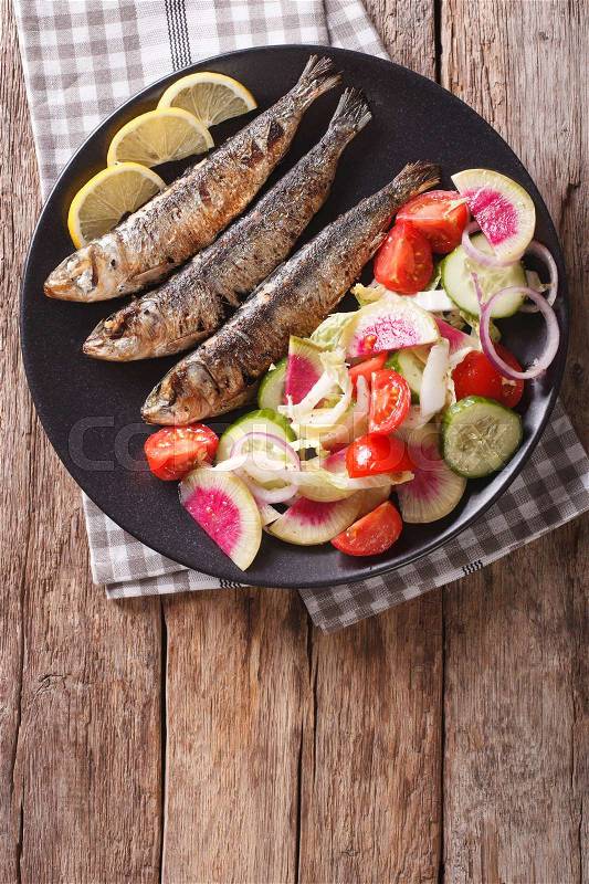 Mediterranean cuisine: grilled sardines with fresh vegetable salad close-up on a plate. vertical view from above\, stock photo