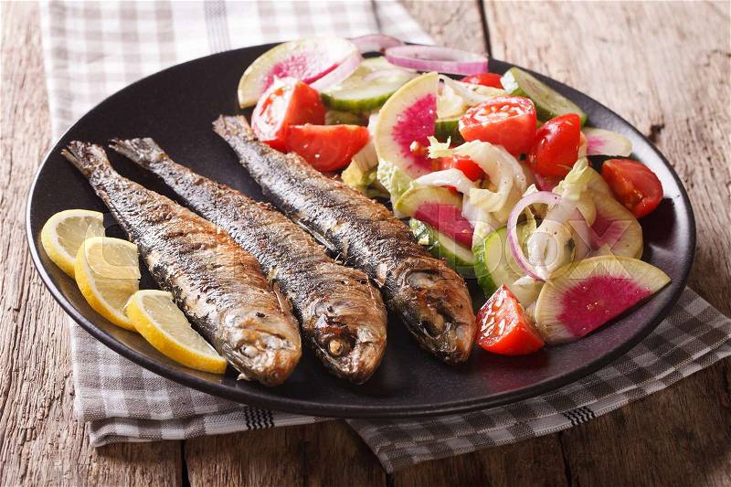 Mediterranean food: grilled sardines with fresh vegetable salad close-up on a plate. horizontal , stock photo
