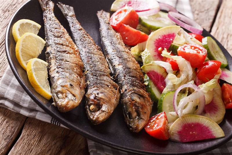 Mediterranean cuisine: grilled sardines with fresh vegetable salad close-up on a plate. horizontal , stock photo