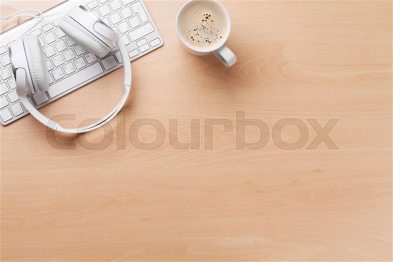 Headphones over keyboard and coffee cup on office wooden desk table. Music concept. Top view with copy space, stock photo