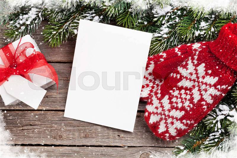 Christmas greeting card, fir tree, mittens and gift box on wooden table. Top view with copy space, stock photo
