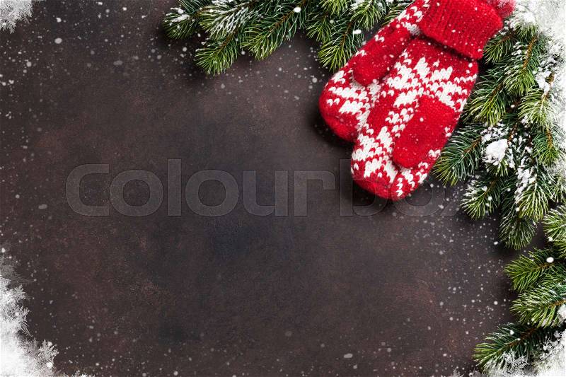 Christmas fir tree and mittens over stone background. Top view with copyspace, stock photo