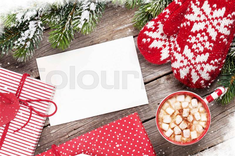 Christmas greeting card, fir tree, mittens, gift boxes and hot chocolate on wooden table. Top view with copy space, stock photo