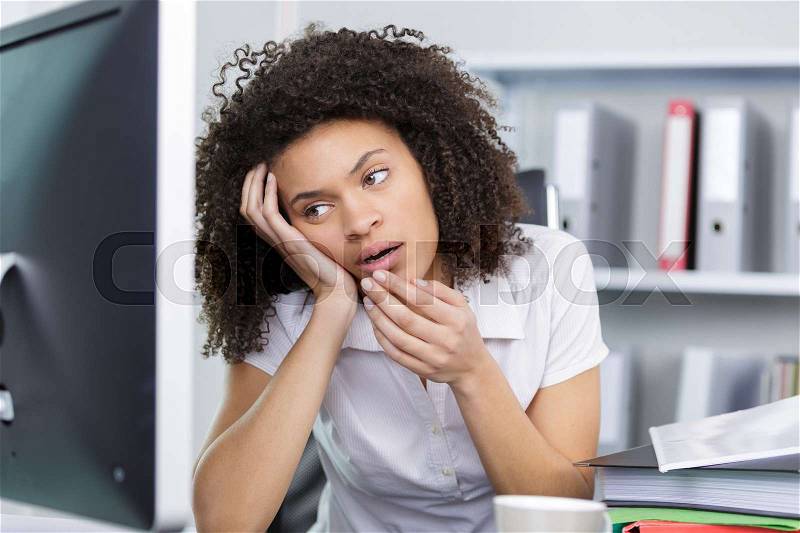 Young woman tired in front her computer at work, stock photo