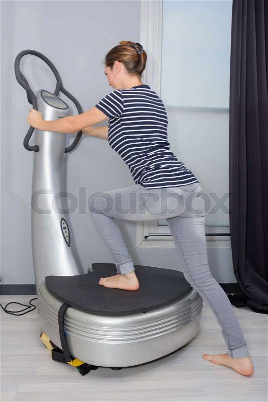 Woman stepping onto fitness machine, stock photo