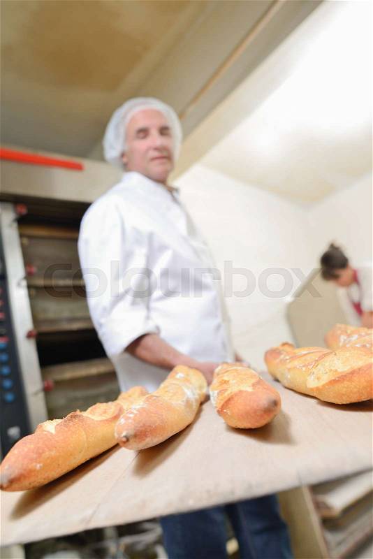 Baker holding five baguettes on paddle, stock photo